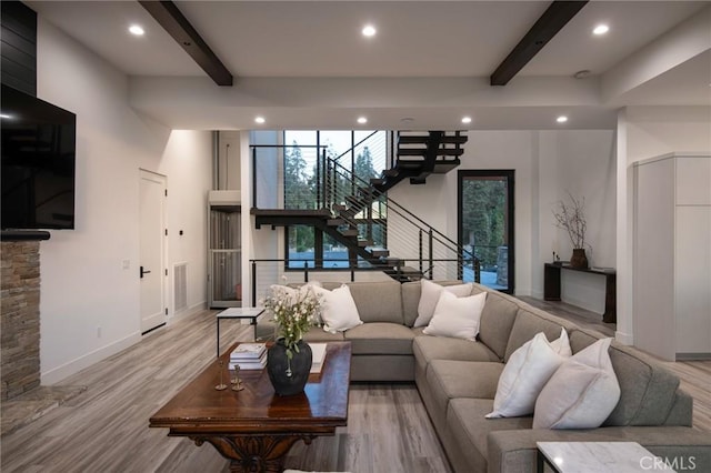 living room featuring beam ceiling, a towering ceiling, and light wood-type flooring