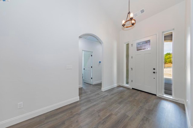 entryway with a towering ceiling, an inviting chandelier, and hardwood / wood-style floors