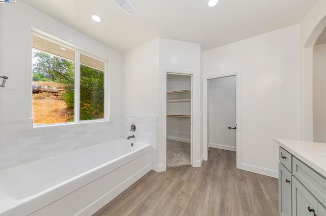 bathroom with vanity, a tub to relax in, and hardwood / wood-style floors