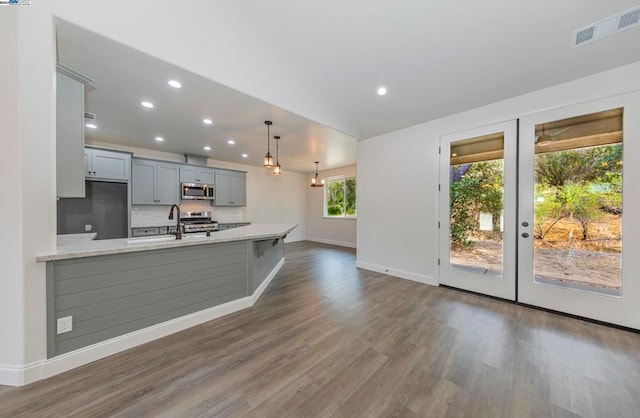 kitchen featuring kitchen peninsula, hanging light fixtures, gray cabinetry, stainless steel appliances, and dark hardwood / wood-style flooring