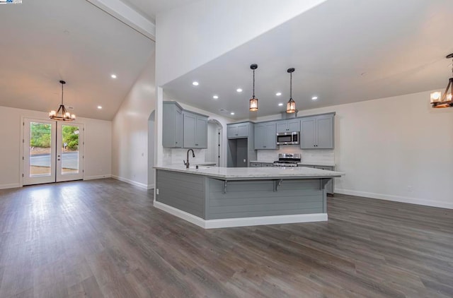 kitchen featuring light stone countertops, appliances with stainless steel finishes, dark hardwood / wood-style floors, and hanging light fixtures