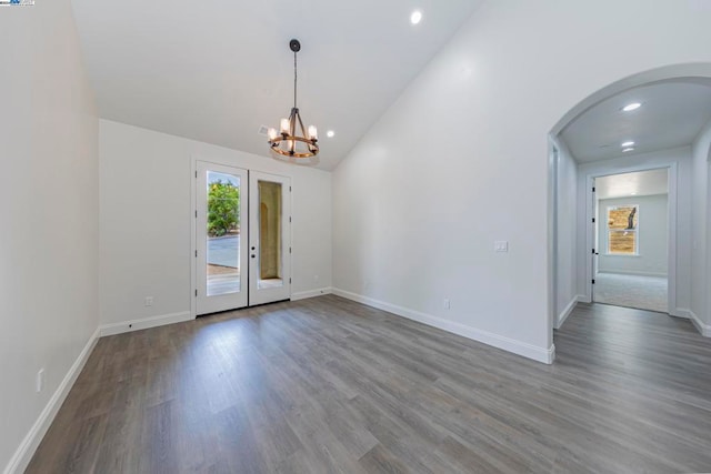 spare room with an inviting chandelier, hardwood / wood-style floors, high vaulted ceiling, and french doors