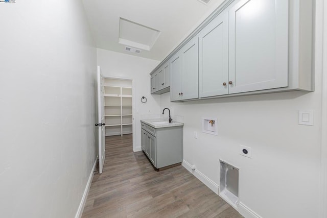 washroom featuring hookup for a washing machine, hookup for an electric dryer, sink, cabinets, and light hardwood / wood-style floors