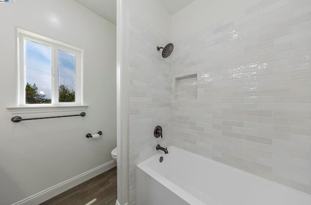 bathroom with toilet, tiled shower / bath combo, and wood-type flooring