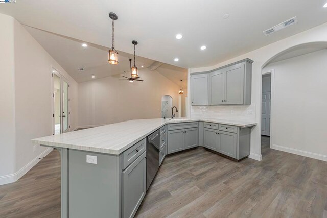 kitchen with sink, dishwasher, kitchen peninsula, gray cabinets, and hardwood / wood-style flooring