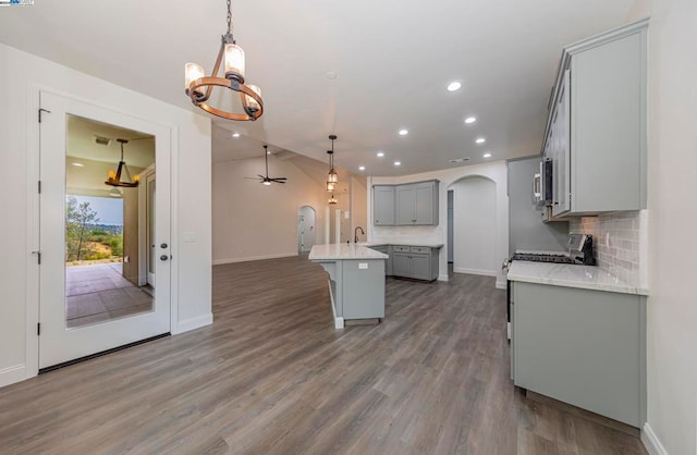 kitchen featuring gray cabinets, dark hardwood / wood-style flooring, a center island with sink, and hanging light fixtures