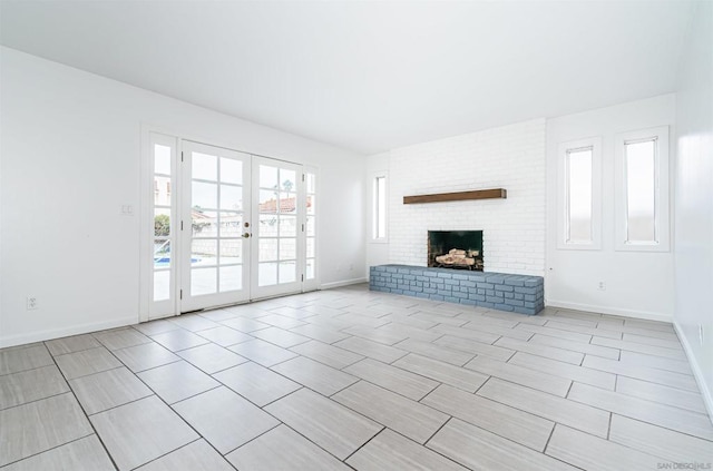 unfurnished living room featuring french doors and a brick fireplace