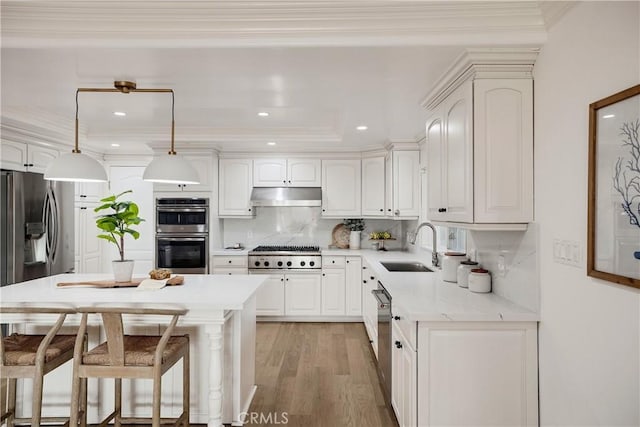 kitchen with sink, decorative light fixtures, appliances with stainless steel finishes, decorative backsplash, and white cabinets