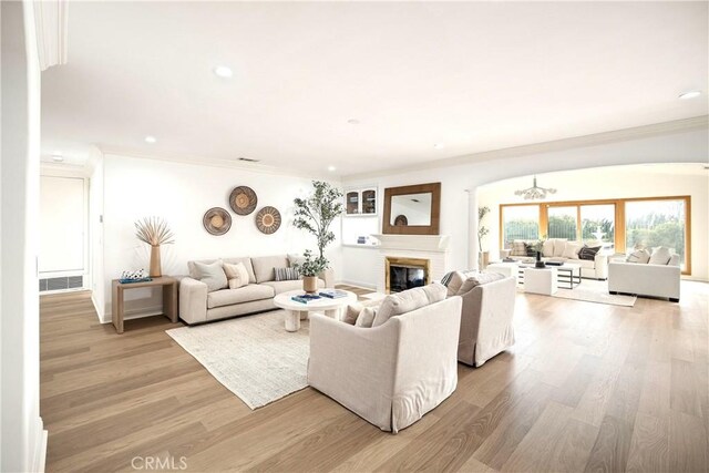 living room featuring light hardwood / wood-style floors, crown molding, and a fireplace