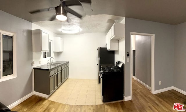 kitchen with black gas range, sink, white cabinetry, and light wood-type flooring