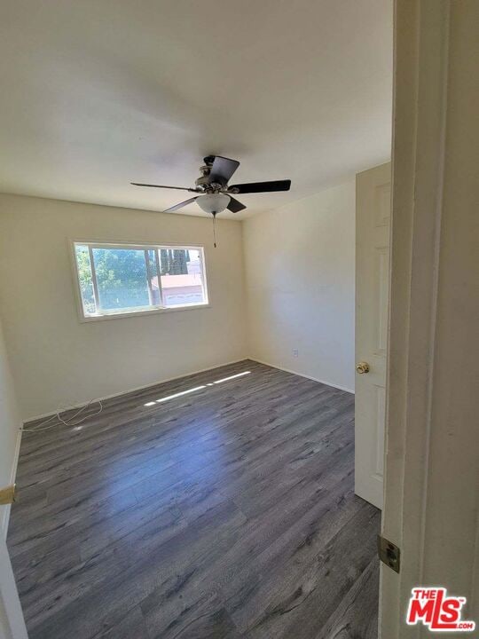 unfurnished room with ceiling fan and dark hardwood / wood-style flooring