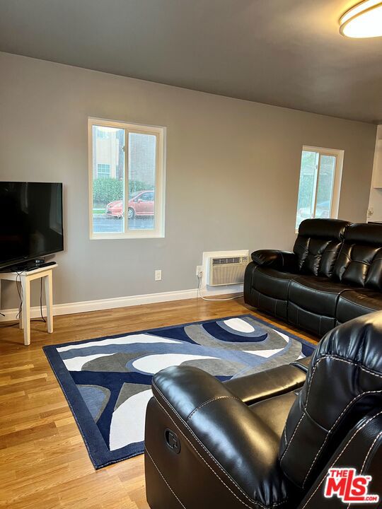 living room featuring light hardwood / wood-style floors and a wall unit AC