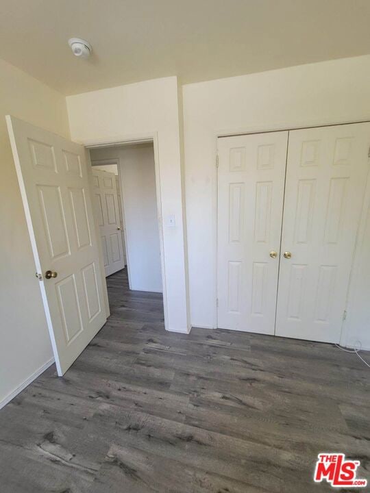 unfurnished bedroom featuring a closet and dark wood-type flooring