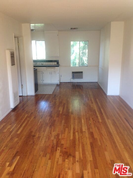 unfurnished living room with hardwood / wood-style floors and a wall mounted AC