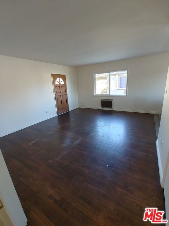 interior space featuring a wall unit AC and dark wood-type flooring