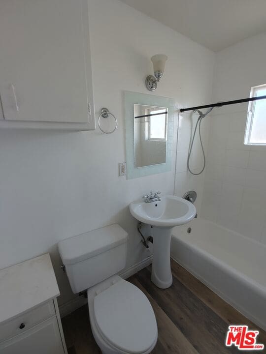 bathroom featuring toilet, tiled shower / bath combo, and wood-type flooring