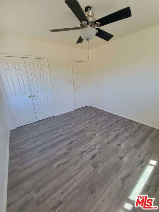 unfurnished bedroom with wood-type flooring, a closet, and ceiling fan