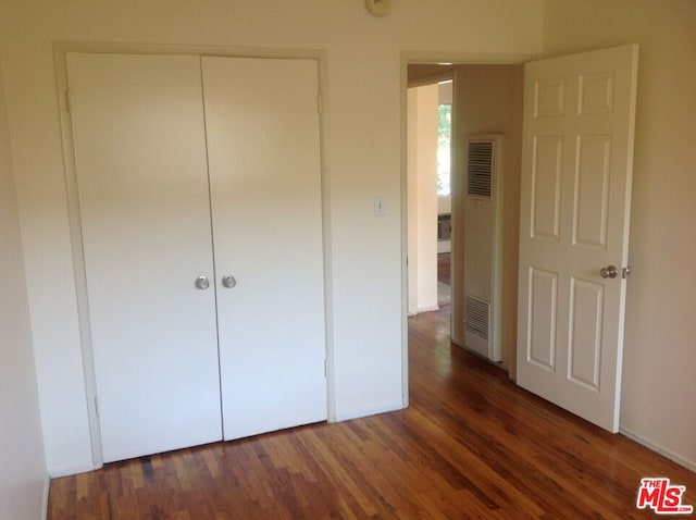 unfurnished bedroom with a closet and dark hardwood / wood-style flooring