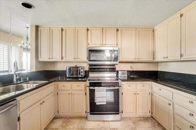 kitchen featuring cream cabinets, appliances with stainless steel finishes, an inviting chandelier, a textured ceiling, and sink