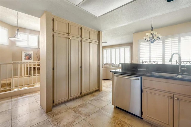 kitchen featuring sink, dishwasher, cream cabinetry, a textured ceiling, and decorative light fixtures