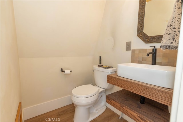 bathroom featuring toilet, sink, and wood-type flooring