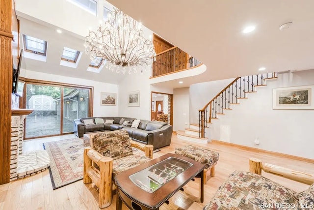 living room with a chandelier, light hardwood / wood-style flooring, high vaulted ceiling, and a skylight