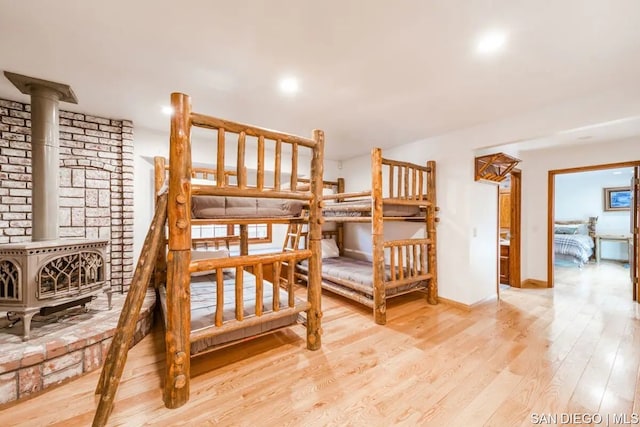 bedroom featuring a wood stove and light hardwood / wood-style flooring