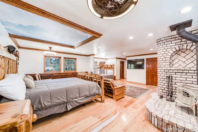 bedroom featuring light hardwood / wood-style flooring, ornamental molding, and a wood stove