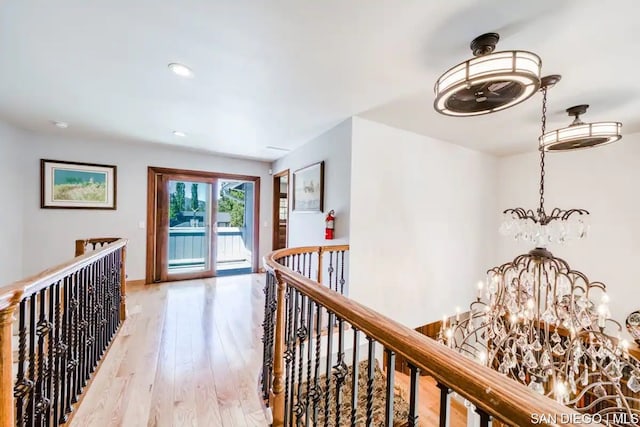 hall with light wood-type flooring and an inviting chandelier