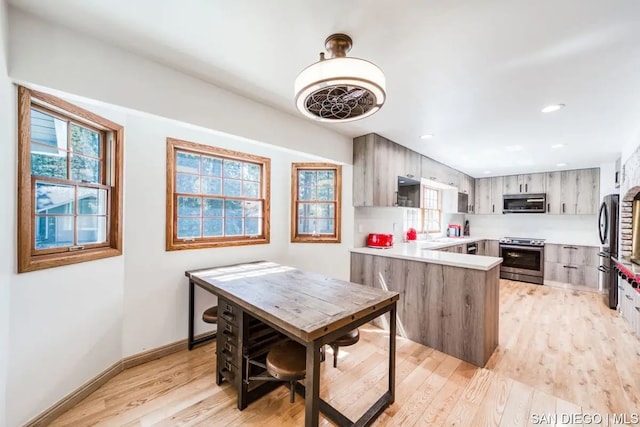 kitchen featuring light wood-type flooring, stainless steel appliances, and kitchen peninsula