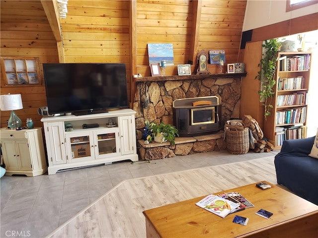 living room with wood ceiling, lofted ceiling with beams, a wood stove, wooden walls, and light hardwood / wood-style flooring