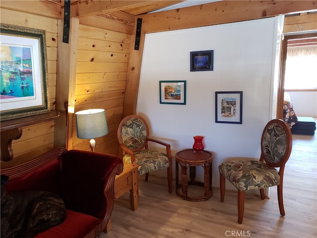 living area featuring hardwood / wood-style floors, a barn door, and wooden walls