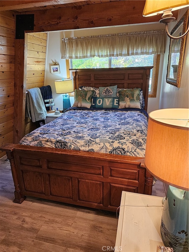 bedroom with hardwood / wood-style flooring and wooden walls