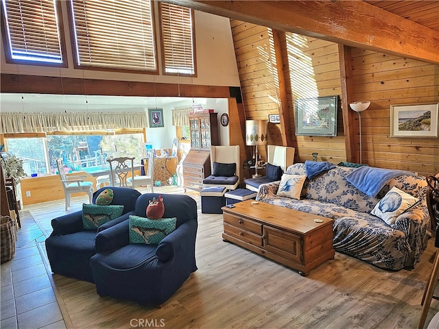 living room featuring high vaulted ceiling, wood walls, beamed ceiling, and light wood-type flooring