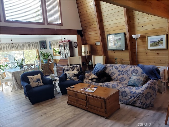 living room with beam ceiling, wooden walls, wood-type flooring, and high vaulted ceiling