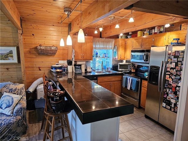 kitchen featuring sink, a kitchen breakfast bar, hanging light fixtures, stainless steel appliances, and light tile patterned floors