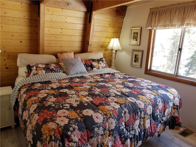 bedroom featuring hardwood / wood-style flooring and wood walls