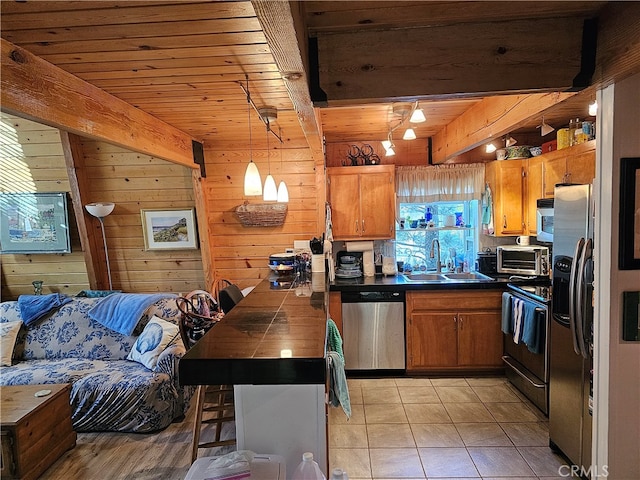 kitchen featuring light tile patterned flooring, beamed ceiling, sink, pendant lighting, and stainless steel appliances