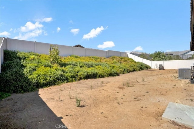 view of yard with central air condition unit and fence