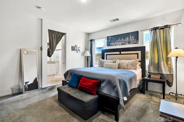 bedroom featuring baseboards, visible vents, carpet floors, and ensuite bath