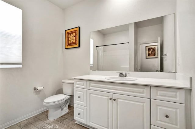 bathroom featuring toilet, vanity, curtained shower, and baseboards