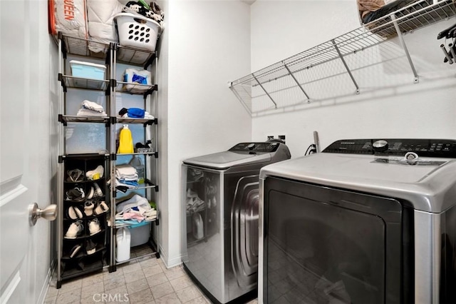 clothes washing area featuring washing machine and clothes dryer, baseboards, and laundry area