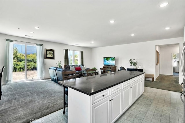 kitchen featuring a center island, open floor plan, dark countertops, and white cabinets