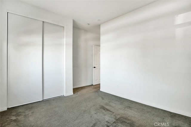 unfurnished bedroom with carpet flooring, baseboards, and a closet