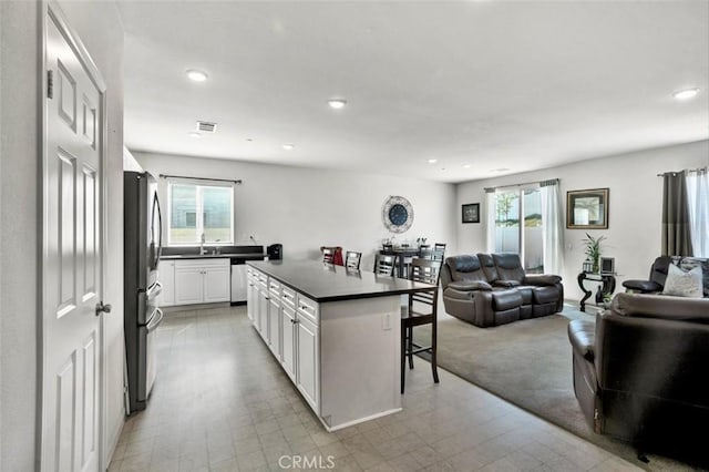 kitchen with open floor plan, white cabinets, dark countertops, and a breakfast bar area