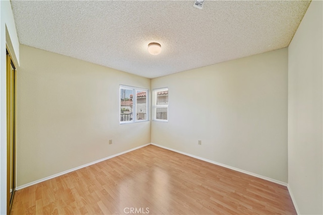 spare room featuring wood-type flooring and a textured ceiling