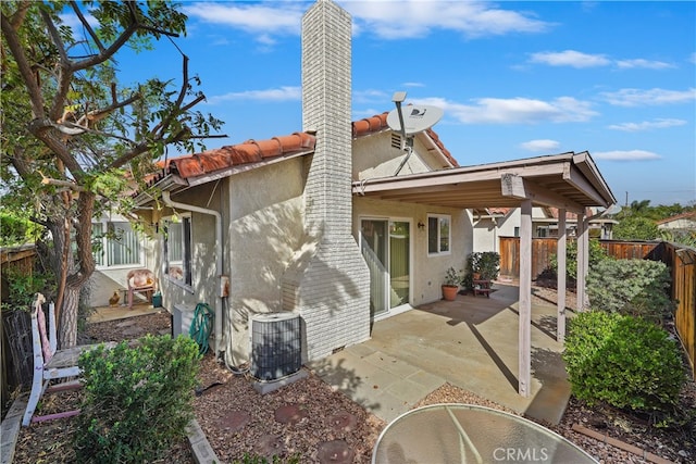 rear view of house with central air condition unit and a patio area