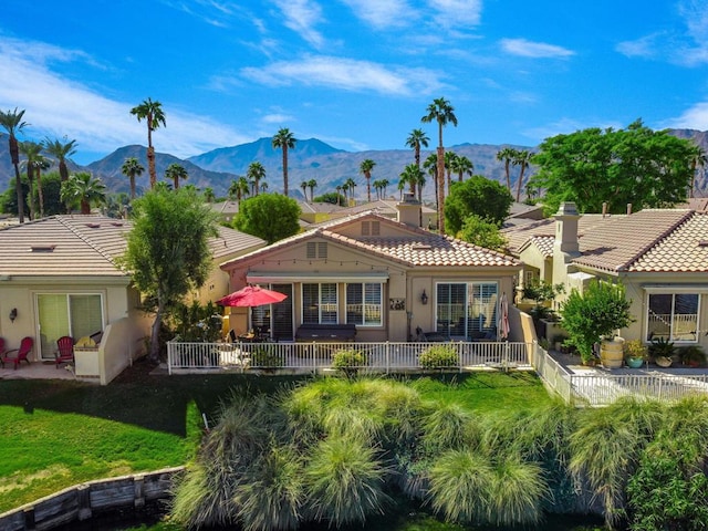 back of house featuring a lawn, a patio area, and a mountain view