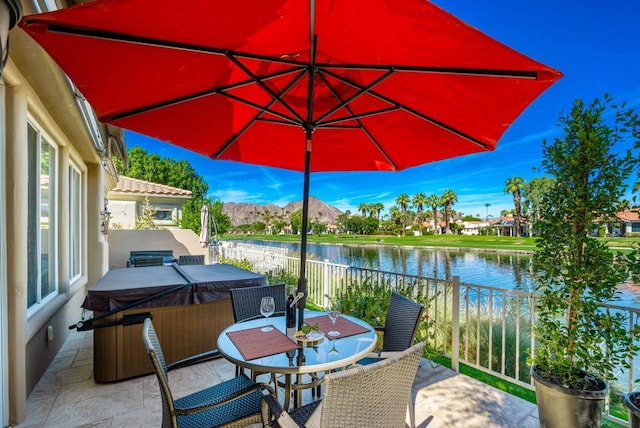 view of patio / terrace featuring a hot tub and a water and mountain view