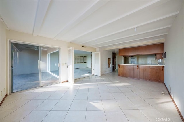 unfurnished living room featuring beamed ceiling and light tile patterned floors